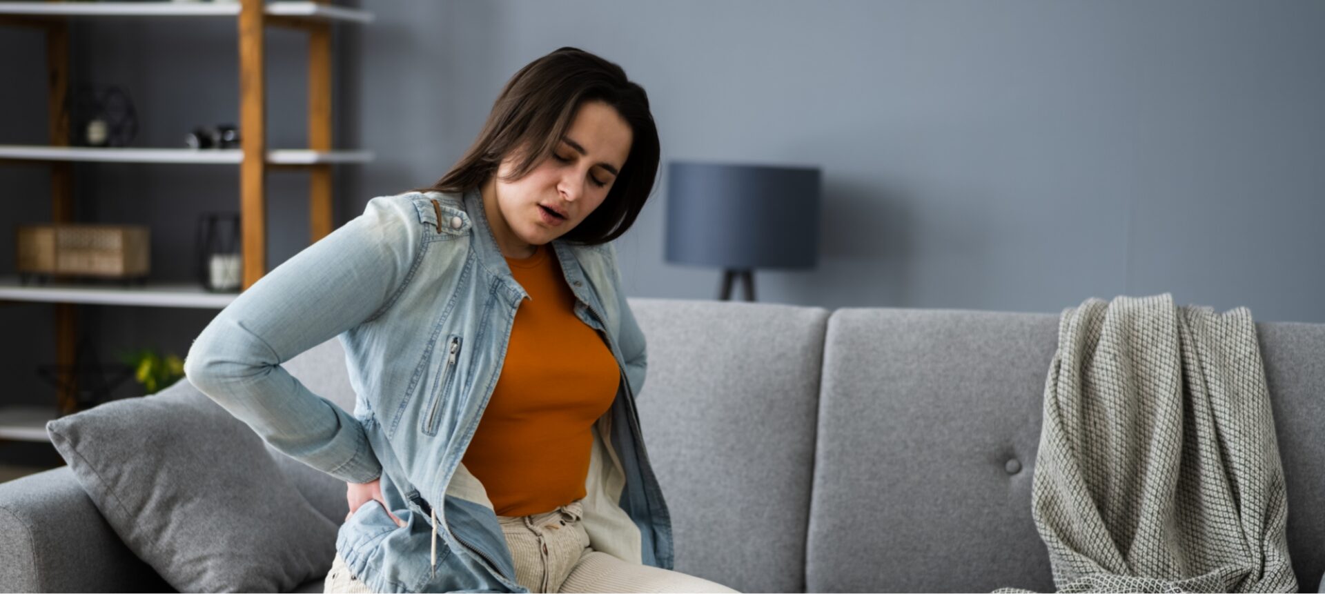 A woman with her hand on her lower back due to back pain from a car accident