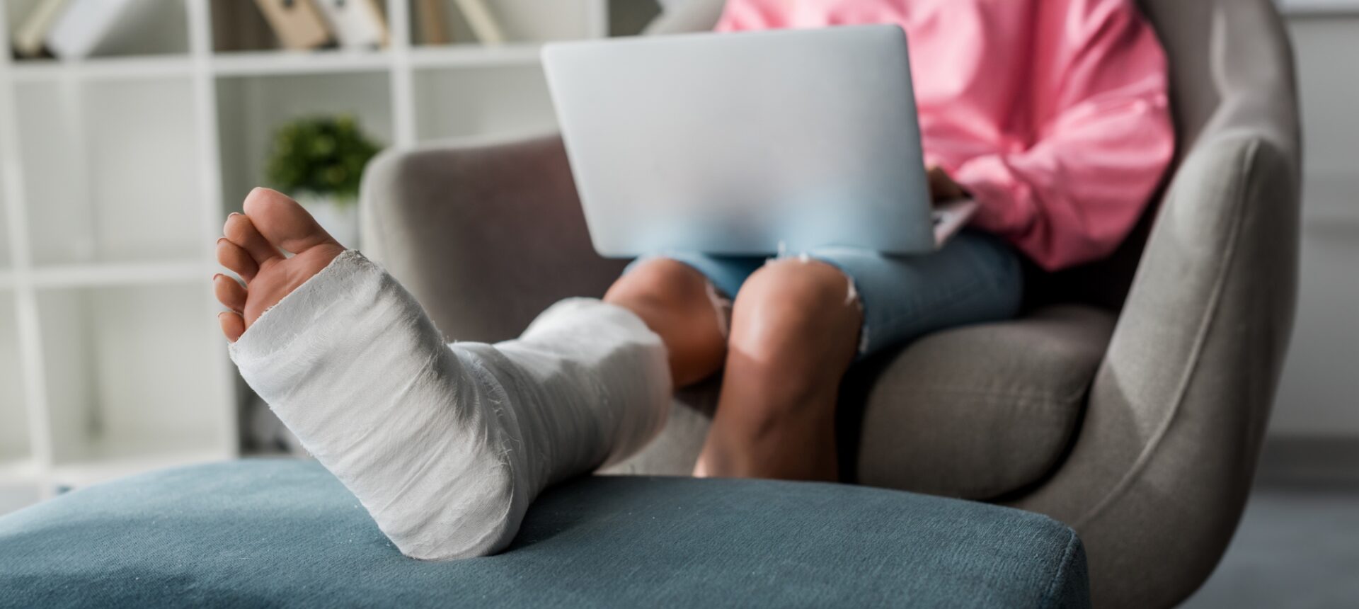 A person sitting on the couch with their foot propped up and in a cast from a leg injury