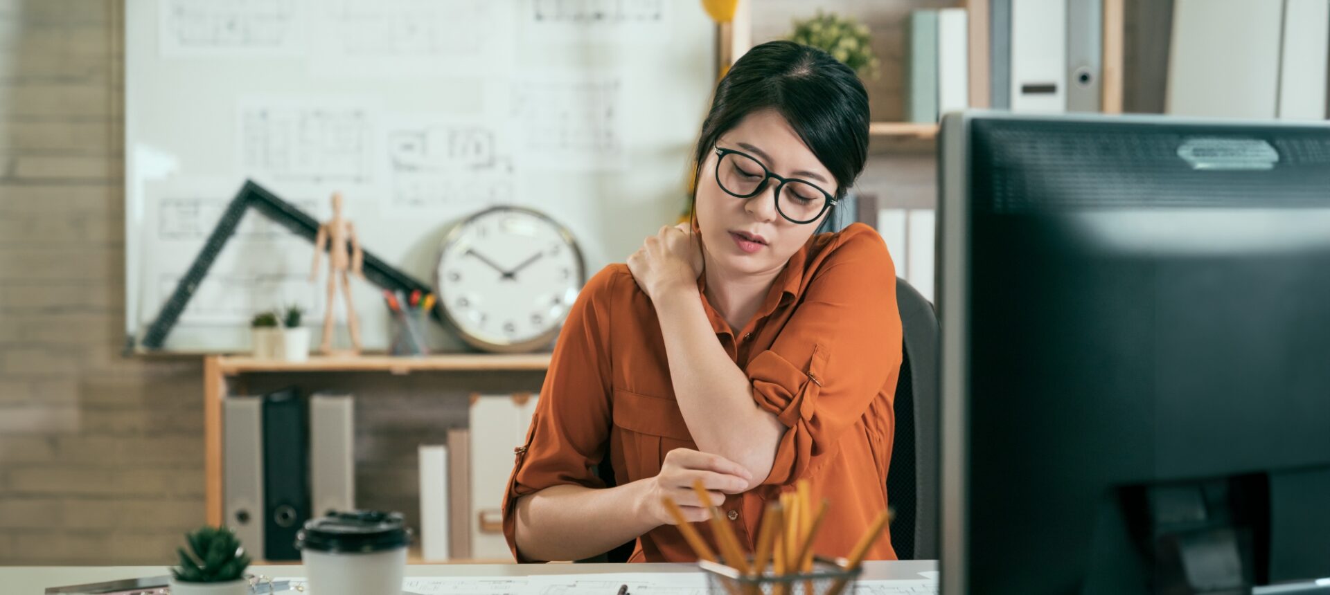 A person seated at a desk and experiencing neck pain after a neck injury